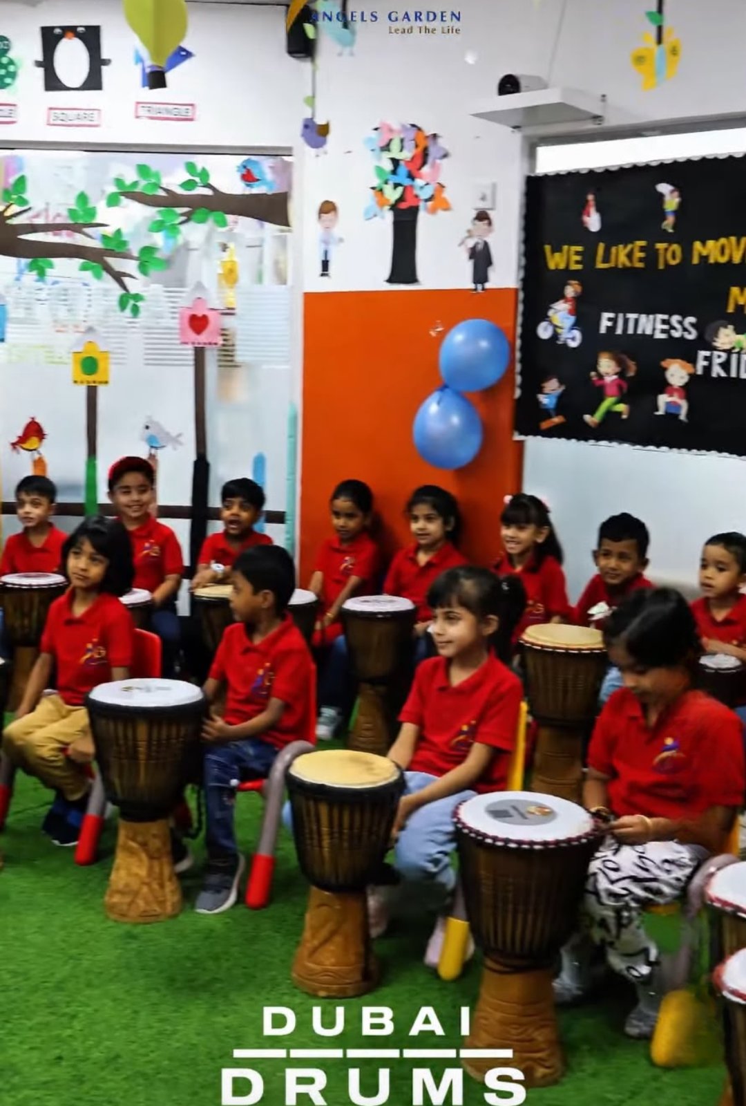 Children in red uniforms enjoying a drumming themed activity day at Angels Garden